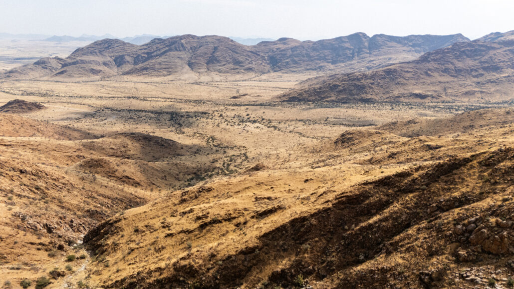 Gravel road through Spreetshoogte Pass in midday light with vast desert landscape.