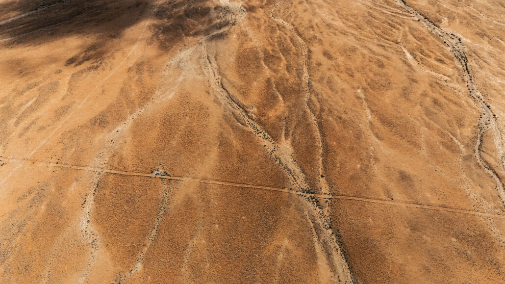 View from a 4x4 on Namibia’s D707 - remote gravel track framed by towering rocky hills and desert light.