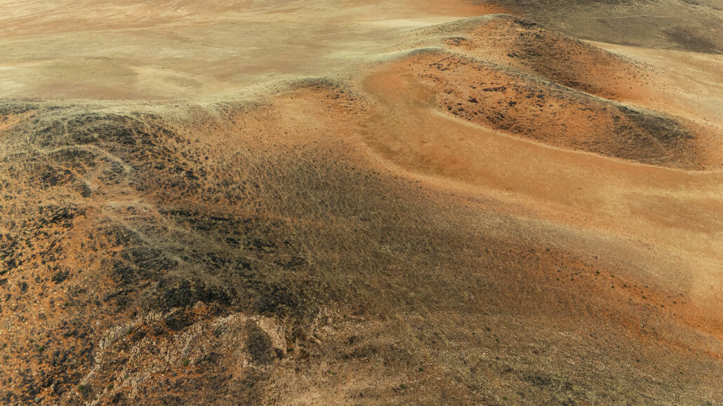 Golden-hour sunlight casting shadows over the dunes and mountains along Namibia’s dramatic D707 route.
