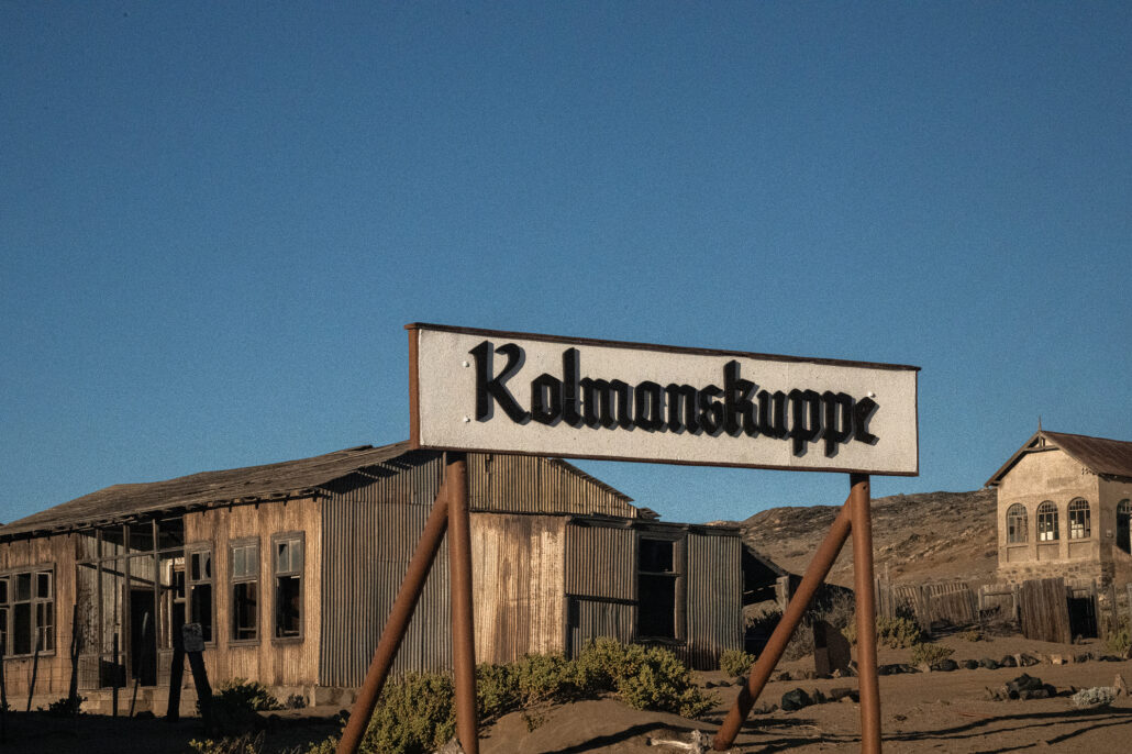 Vintage signage on an old Kolmanskop building under soft morning sun.