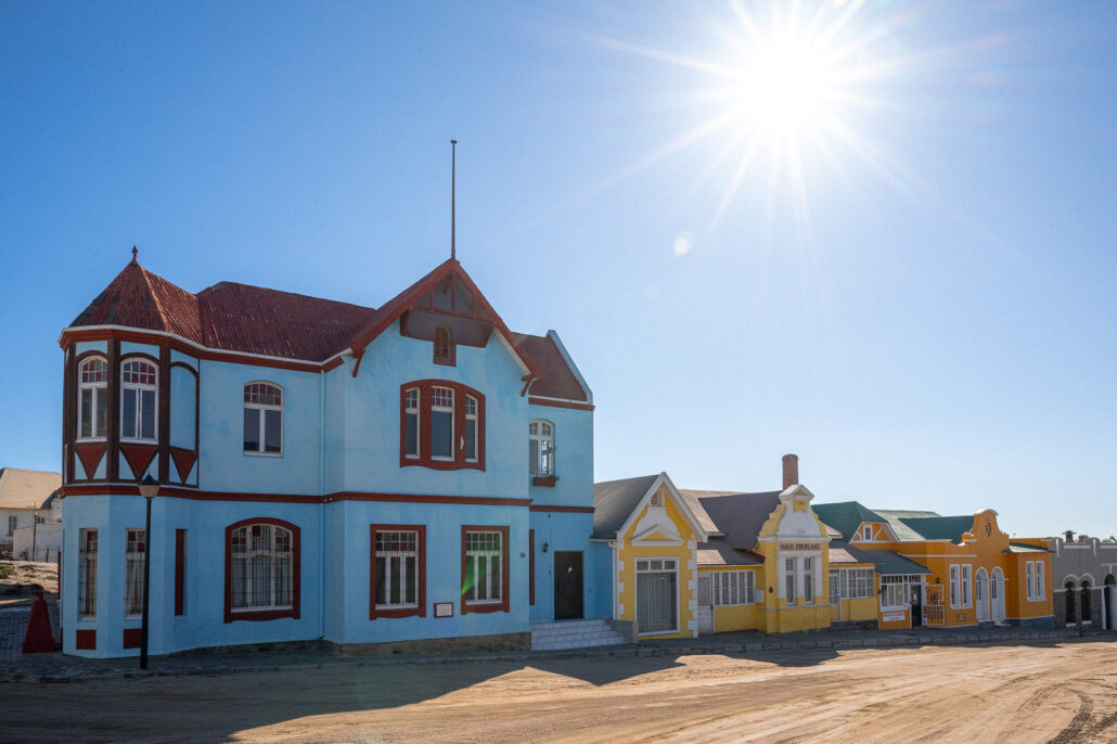 Vibrant colonial-era houses in Lüderitz, Namibia, painted in pastel tones under a blue sky.