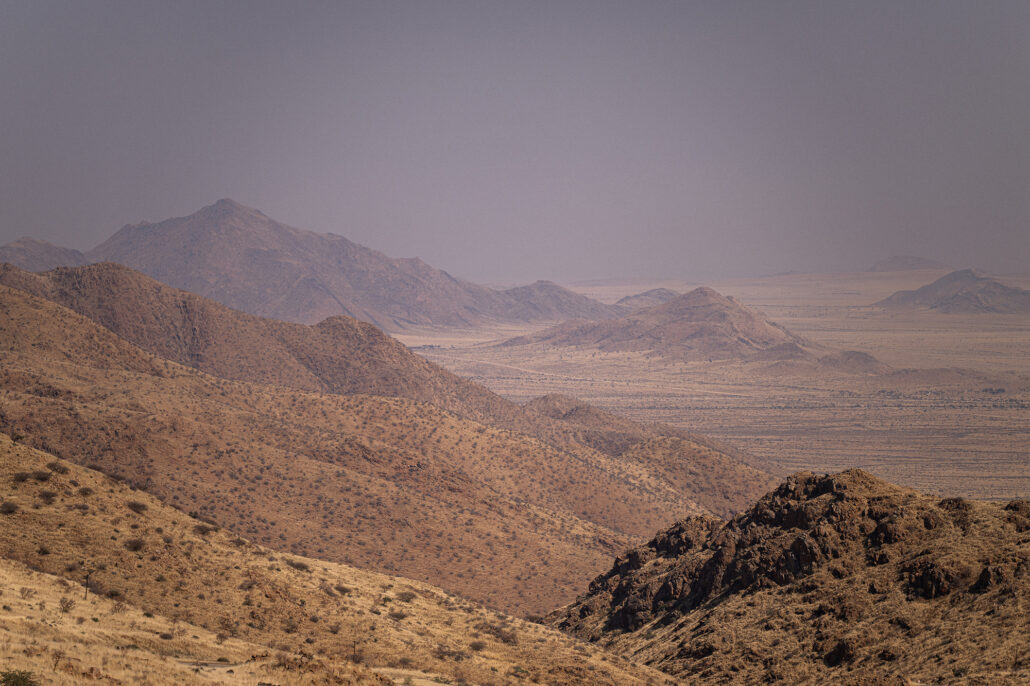 Gravel road through Spreetshoogte Pass in midday light with vast desert landscape.