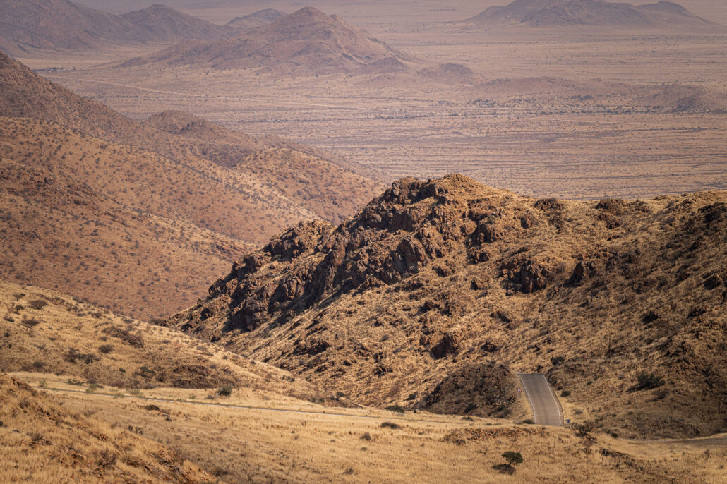 Gravel road through Spreetshoogte Pass in midday light with vast desert landscape.