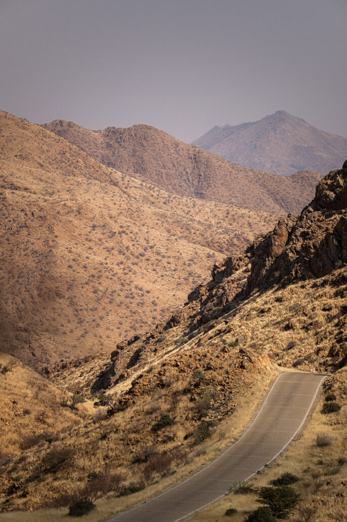 Gravel road through Spreetshoogte Pass in midday light with vast desert landscape.