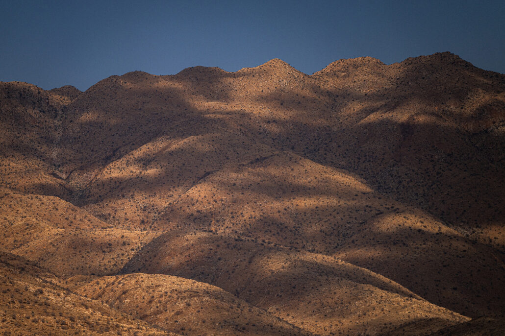 Golden-hour light and shadows dancing over rocky mountain ridges.