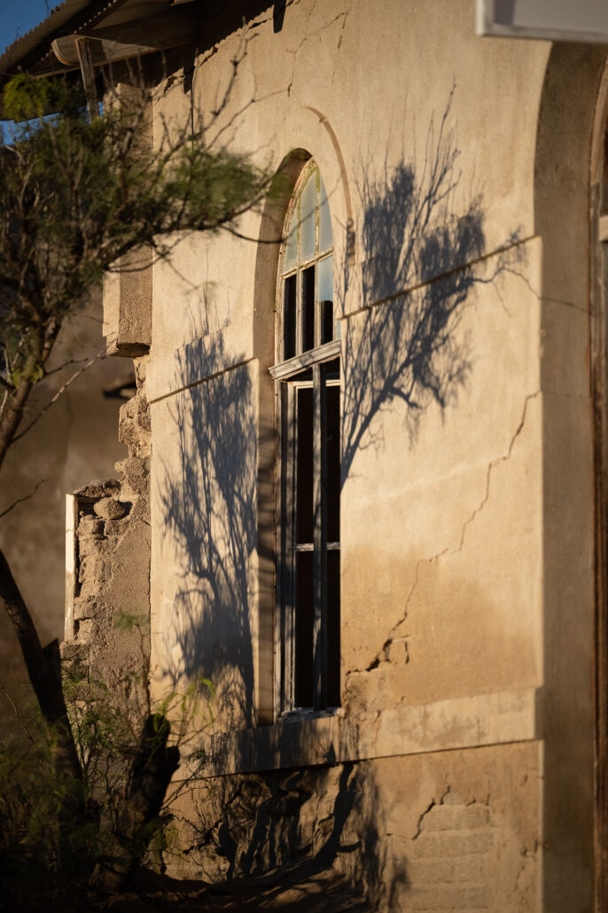 View through multiple doorways in a Kolmanskop house, all filled with desert sand.