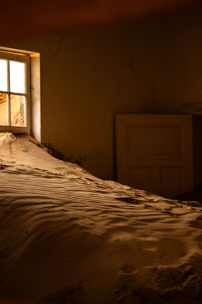 Desert wind shaping ripples in the sand that fills each room of the ghost town.