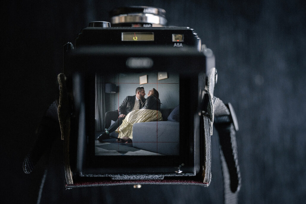 Couple framed inside classic medium-format camera screen, modern romance with vintage touch.