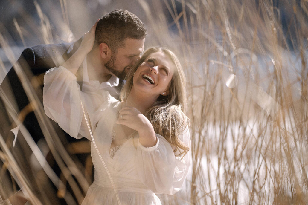 Golden-hour engagement in a pampas grass field in Japan, couple laughing and touching faces, editorial candid storytelling.