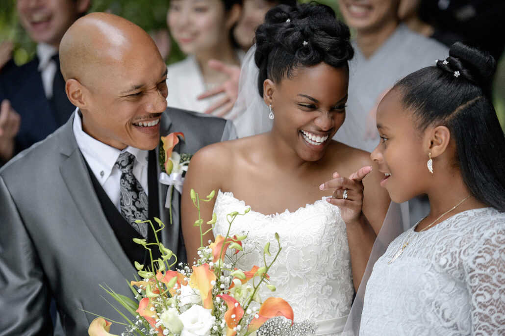 Bride, groom, and daughter sharing a joyful wedding moment, refined using AI editing software for photographers for authentic, natural skin tones.