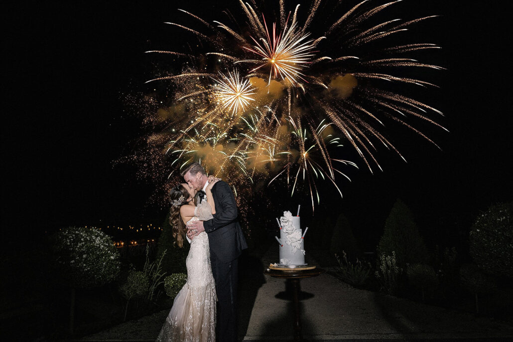 Couple kissing under a night sky fireworks display during their wedding, edited with AI editing software for photographers in the Modern Classic style by 37 Frames Photography.