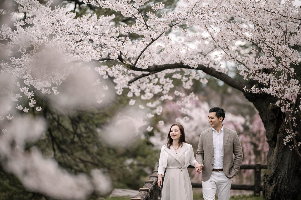 Couple framed by cherry blossoms with Hirosaki Castle in the background during sakura season in Japan