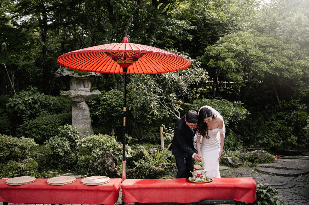 A summer wedding in Japan in lush greens. The couple are opening a small sake barrel called a 'Kagami biraki'. Their wedding on the Izu Peninsula in Japan.