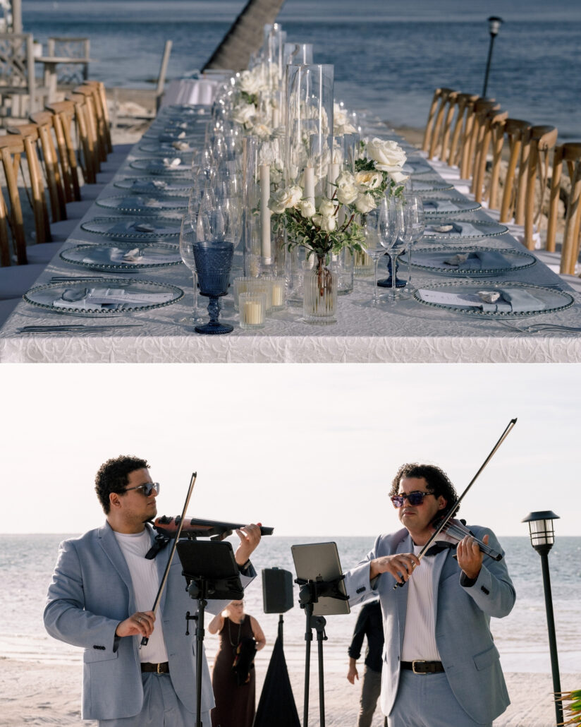 A long table set with white roses, candles and blue glassware by the water, and two violinists in pale blue suits play on the beach in the Florida Keys.