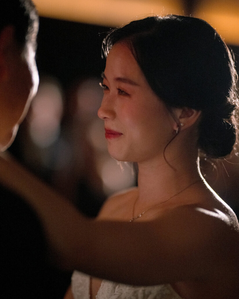 The bride's eyes fill with tears in the warm light of the reception hall as she dances at her ryokan wedding in Japan.