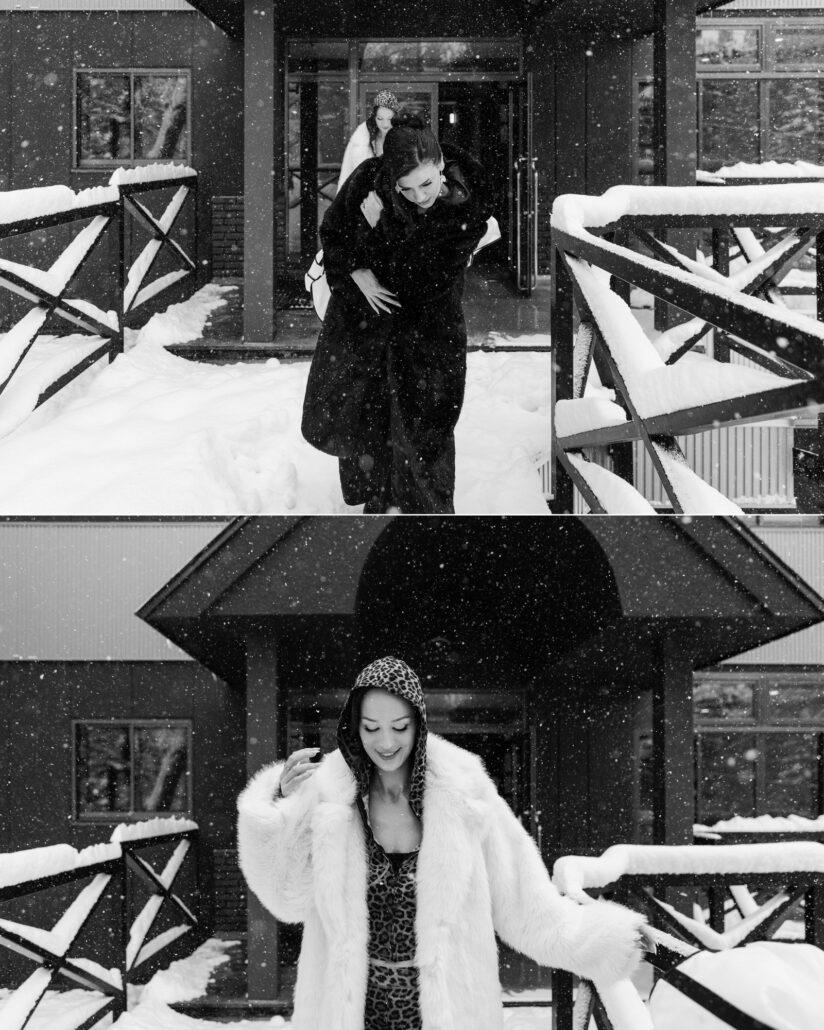 In black and white, a friend in a dark fur coat steps out into the snow, and the bride follows in white faux fur and a leopard hood on her Hakuba wedding day.