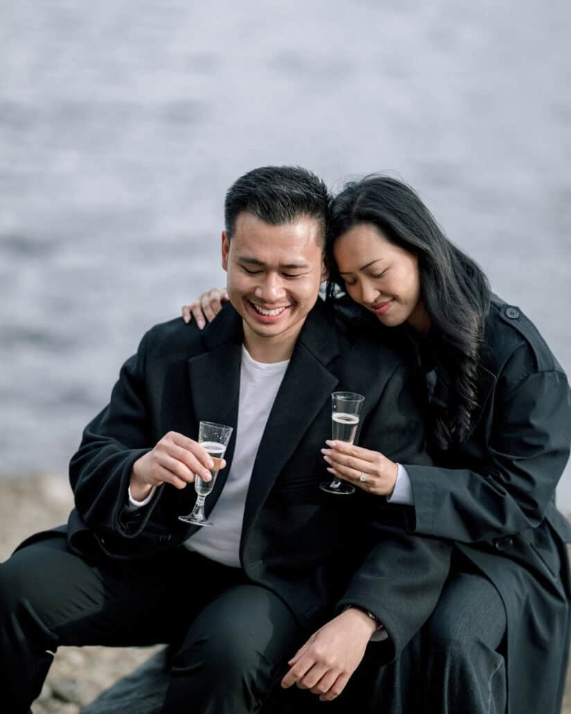 The couple toast with champagne by one of the Fuji Five Lakes after the proposal, her head resting against his.