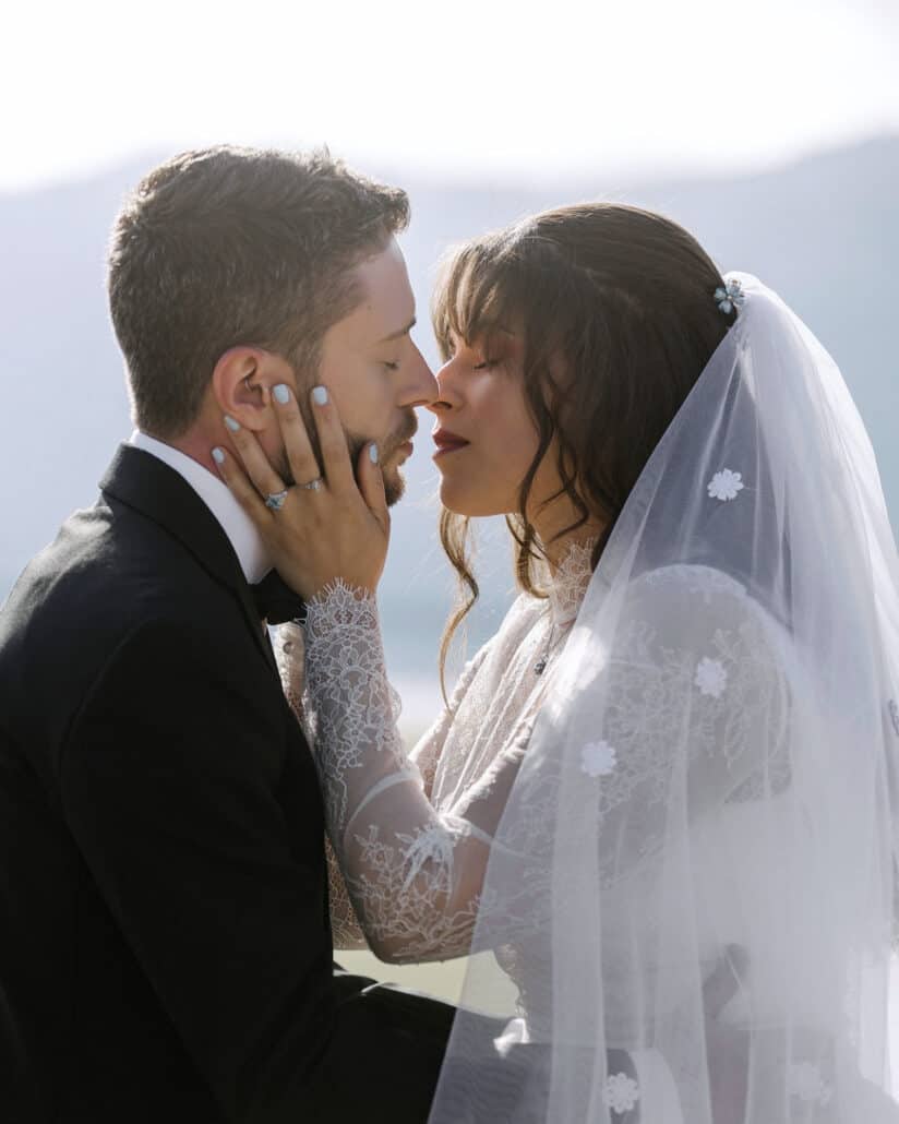 The couple stand nose to nose at their Lake Kawaguchi elopement, the bride's hand on his cheek showing her engagement ring with blue stones.