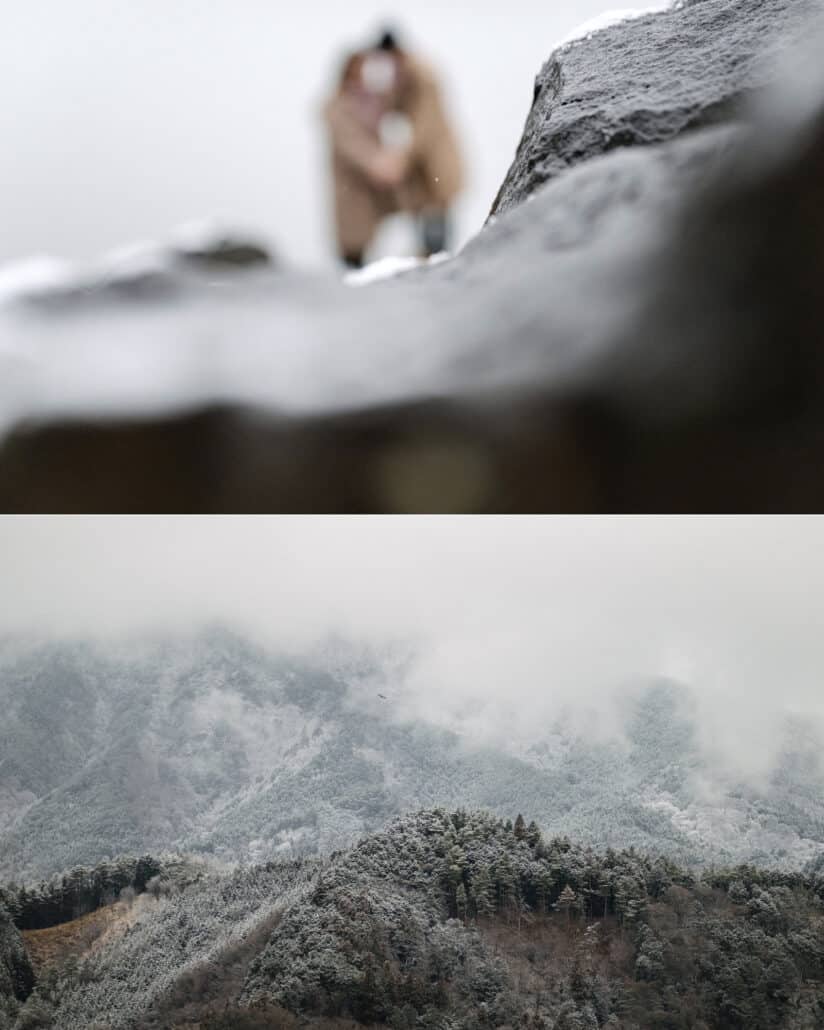 The couple glimpsed beyond a snowy rock, and cloud and snow drifting over the forested mountains around the lake.