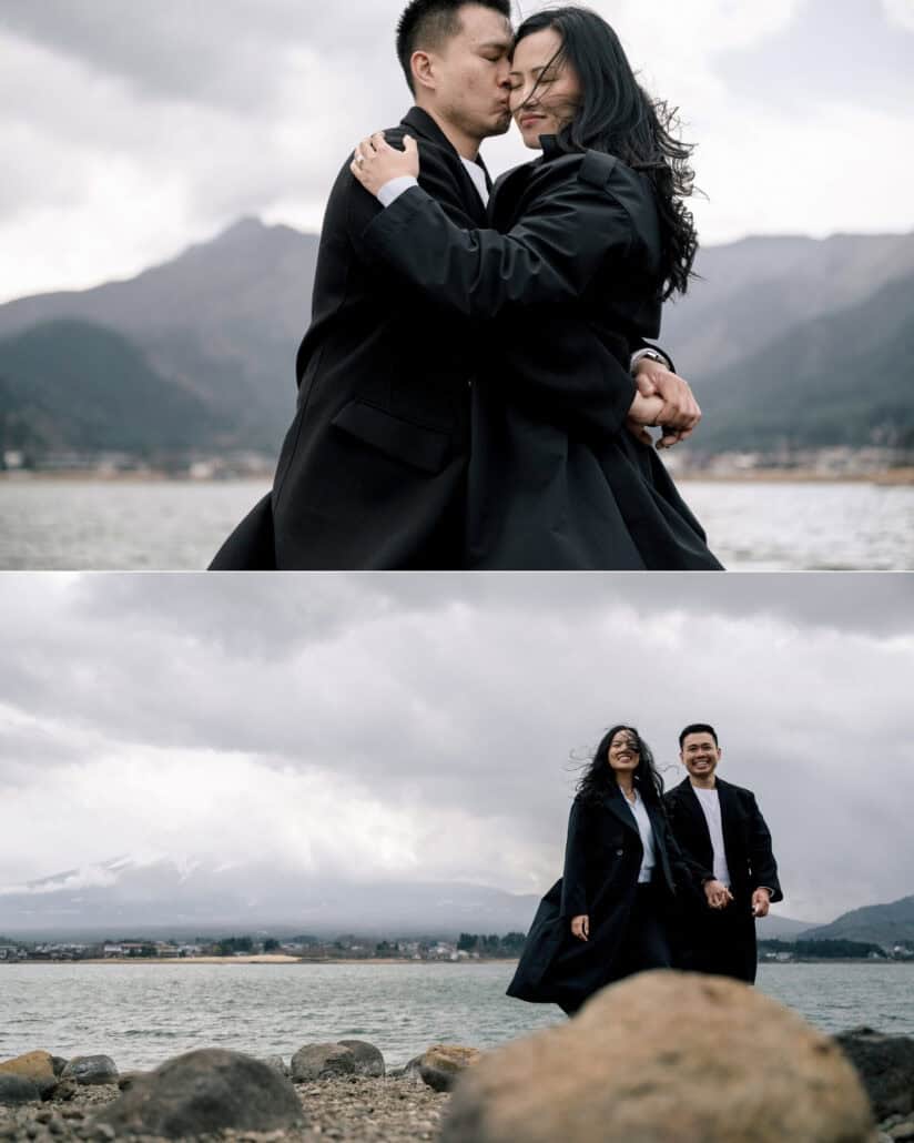 The couple hold each other on the shore of Lake Kawaguchiko, and stand on the rocks by the water, her coat catching the wind.