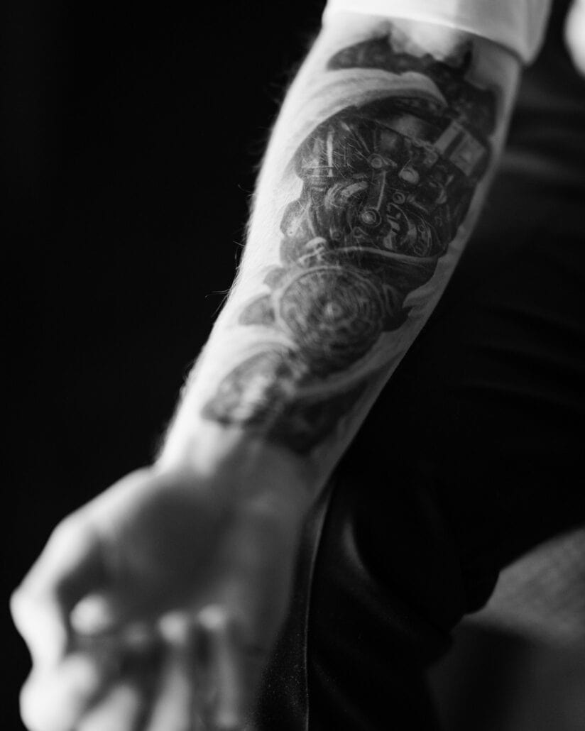 A black and white detail of the groom's tattooed forearm, his white shirt sleeve pushed back, as he gets ready for their elopement in Japan.