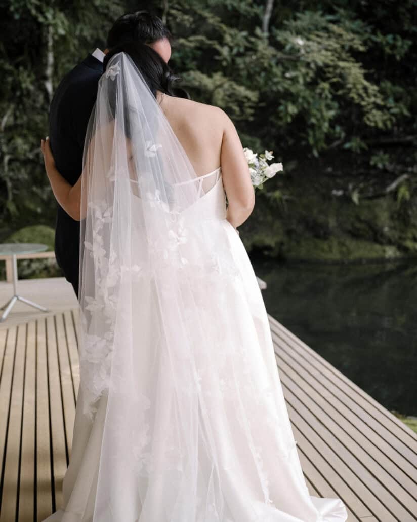 After the first look on the pond deck at Asaba ryokan in Izu, the bride and groom embrace, her appliqué veil falling to the boards.