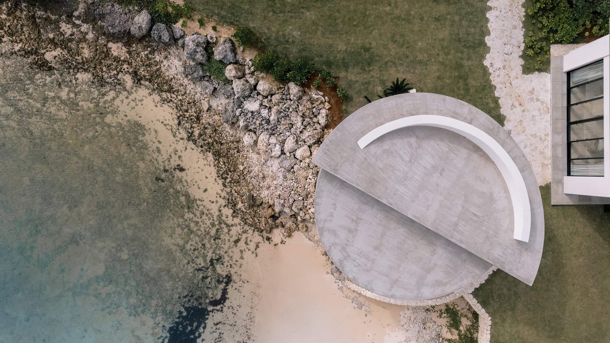 Seen from directly above, the round chapel at Rosewood Miyakojima sits at the water's edge beside reef rocks, a chapel wedding venue in Okinawa.