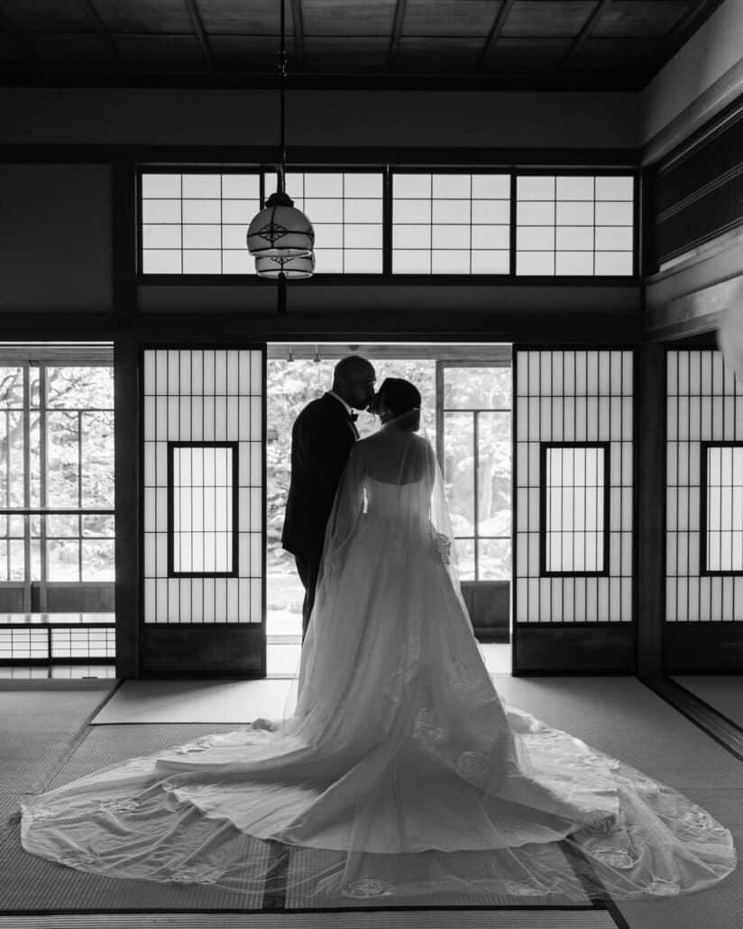 The couple kiss in silhouette between shoji doors, her train spread across the tatami of a traditional Japanese house in Tokyo.