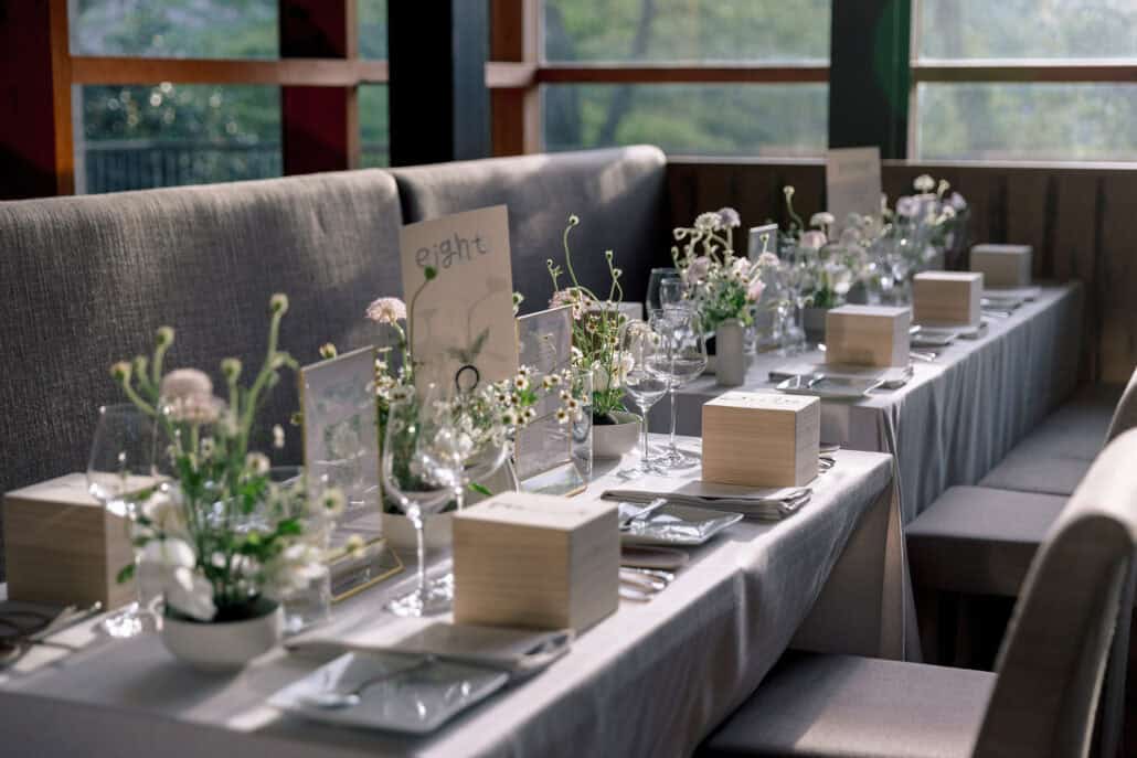 Small wooden boxes holding handmade Kyoto yunomi cups wait on long dinner tables set with wild flowers at a wedding in Hakone, guest gifts made in Japan.