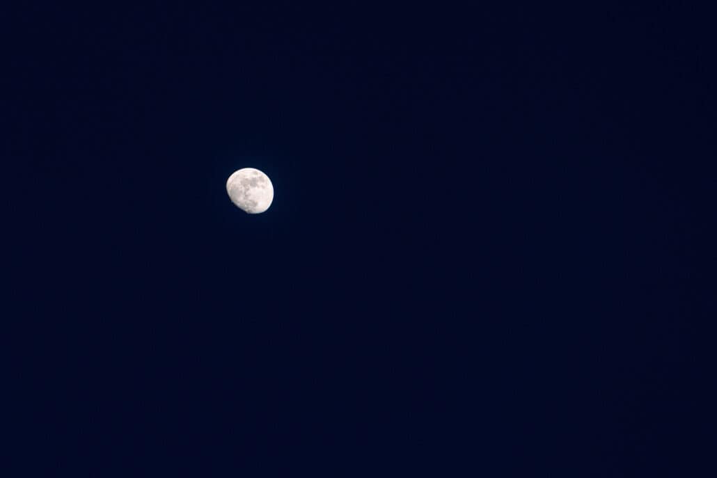 A nearly full moon hangs in a clear navy sky over Miyako Island at the end of the wedding day, its craters soft grey against the dark.