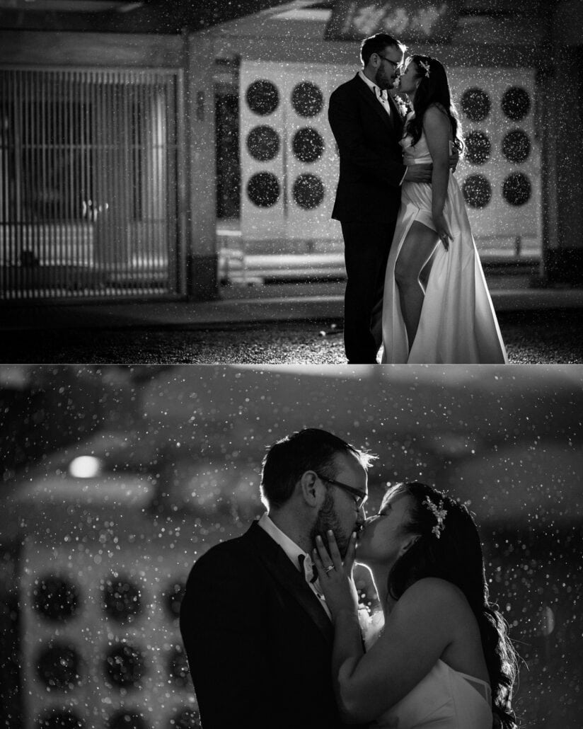 In black and white, the couple kiss in the night rain by the round windows of the Asaba ryokan entrance, full length and close up, lit by flash.