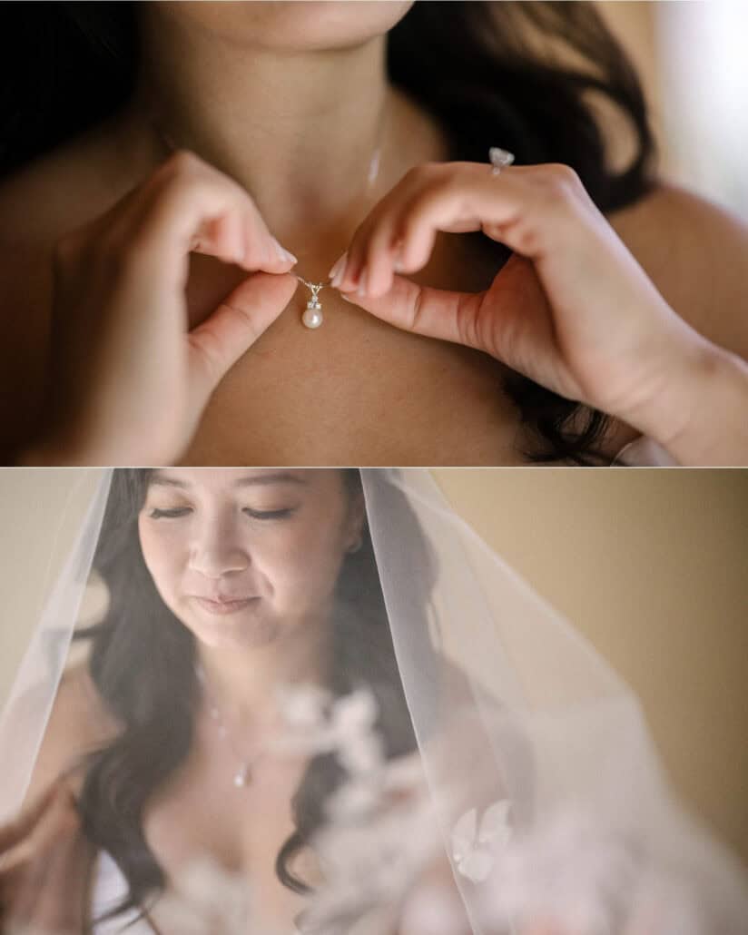 The bride's hands, engagement ring on, hold a pearl pendant at her collarbone, and she looks down under her veil while getting ready at a ryokan.