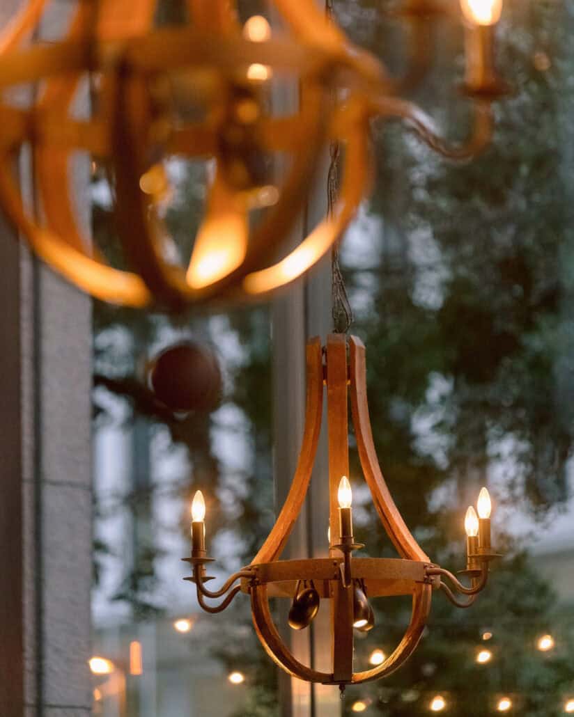 Candlelit chandeliers at a Tokyo wedding reception, with the trees outside blurred through the tall windows.