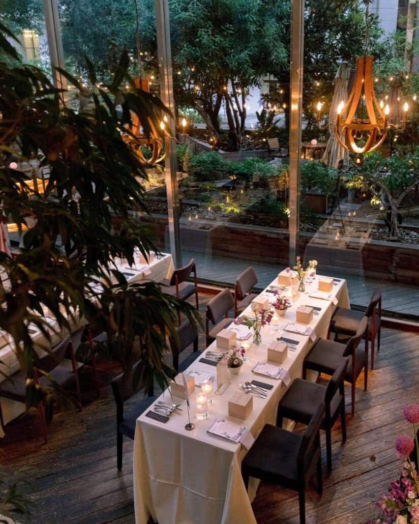 The long table from above, set with candles, flowers and small wooden gift boxes for an intimate wedding reception in Tokyo.