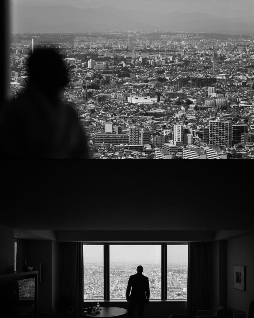 Silhouettes against the windows of the Park Hyatt Tokyo, the city stretching away below, in black and white.