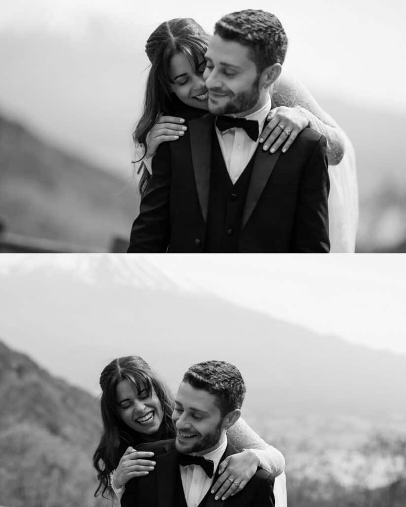 The bride wraps her arms around the groom from behind and they laugh together on a mountain pass above Lake Kawaguchi, Mt Fuji faint in the haze.