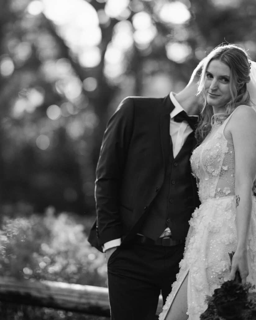 In black and white, the bride leans on the groom and smiles at the camera, his face hidden under her veil, in the garden of their Japan elopement.