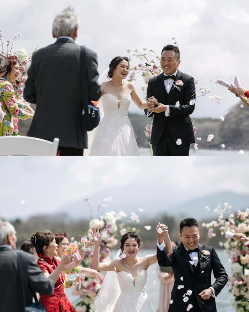 Guests throw petals as the bride and groom leave their Lake Shoji ceremony hand in hand, then raise their arms at a destination wedding in Japan.