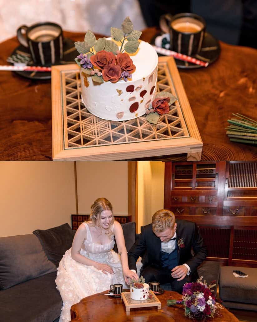 A small white wedding cake with deep red roses sits on a lattice tray between two cups, and the couple laugh over it at their elopement at a ryokan.