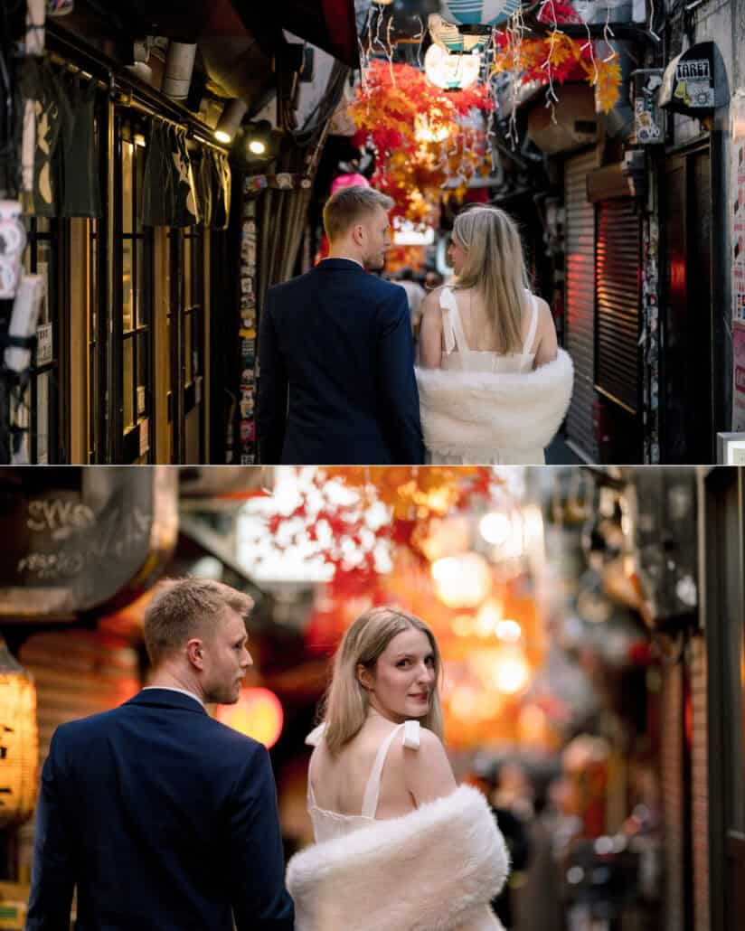 The couple walk a narrow Shinjuku alley of lanterns and red maple leaf decorations as the bride glances back, a Tokyo couple photoshoot.