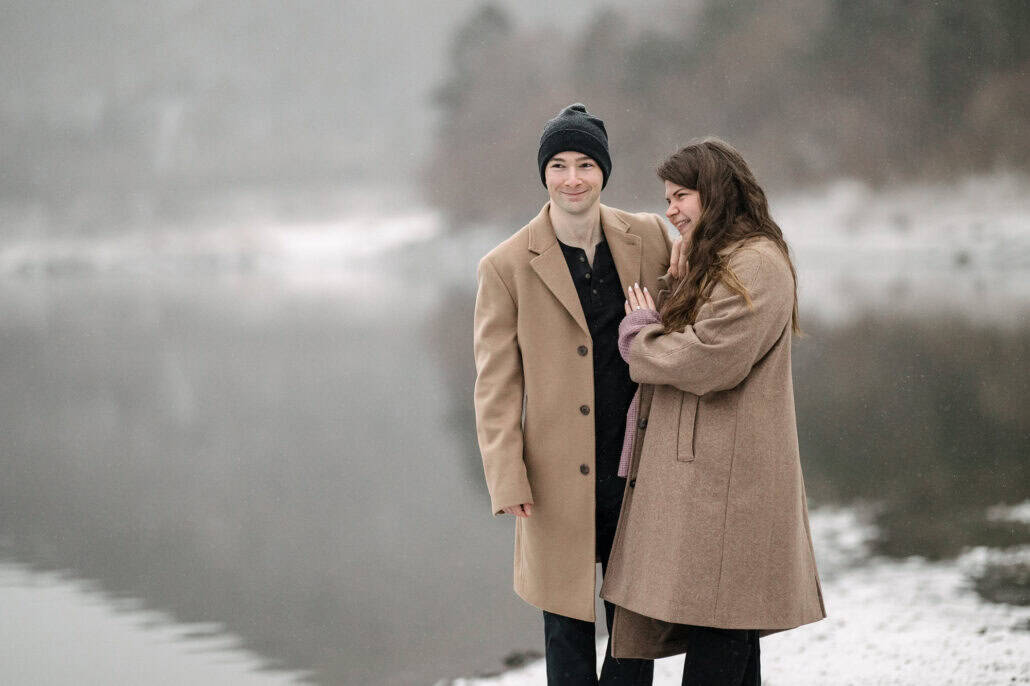 Just engaged, she laughs with her ring hand on his chest as he smiles beside her on a snowy winter lakeshore in Japan.