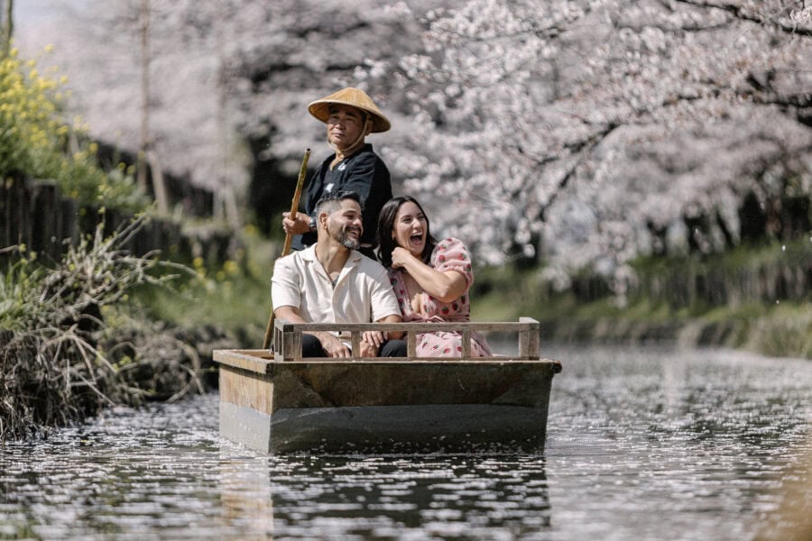 On a cherry blossom boat ride in Kawagoe, a boatman poles the laughing couple down the Shingashi River at their cherry blossom elopement in Japan.