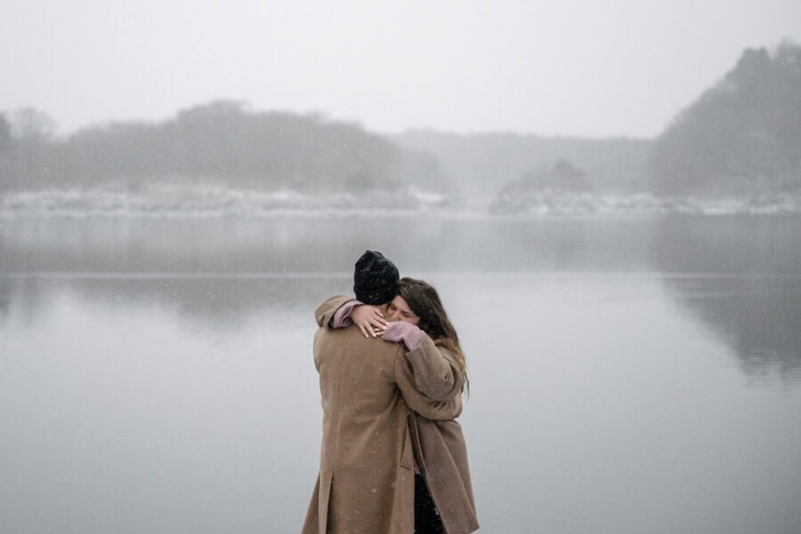Eyes closed, she wraps her arms around his neck as snow falls over Lake Shoji and its misty hills, a winter proposal in Japan.