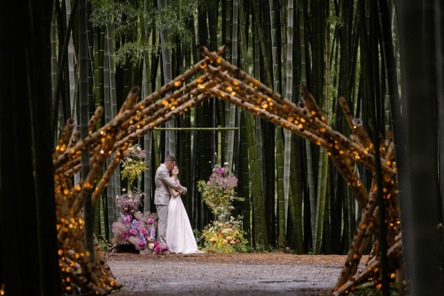 A lit arch of bamboo poles frames the couple at their bamboo grove elopement ceremony in Tochigi, Japan.