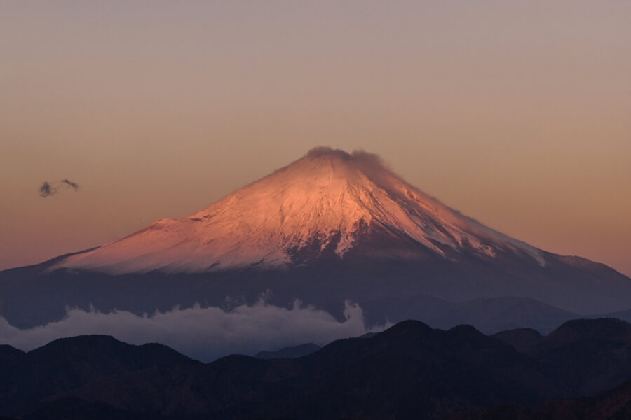 Mt Fuji glows red with snow at sunrise above blue ridges on the morning of a late autumn wedding in Japan.