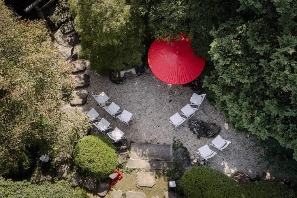 Seen from above, white chairs face a red wagasa in the raked gravel of Tantoku's garden in Kawagoe, set for a Japanese garden wedding.