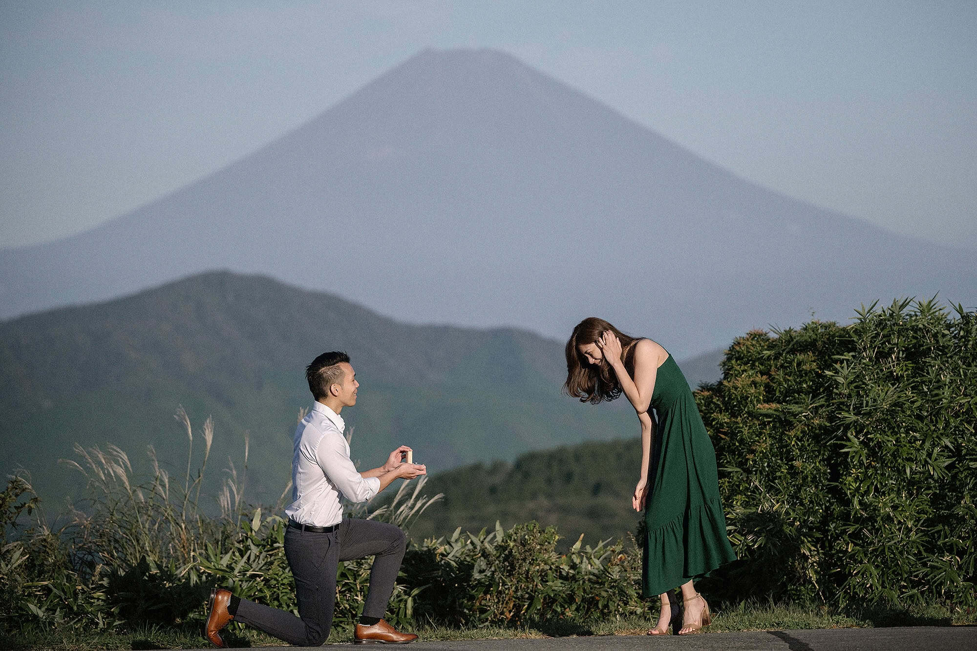 He proposes again on Taikanzan with Mt Fuji huge behind them, and she bends forward with her hand to her face.