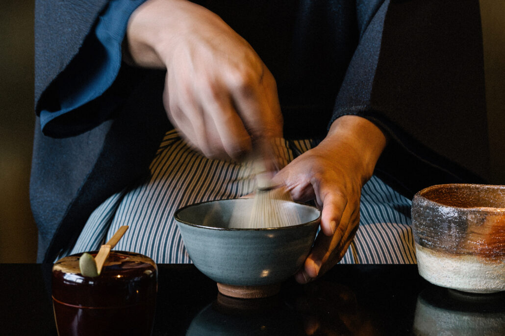 Matcha being whisked by hand in a blue bowl during the tea ceremony that opened a Hokkaido destination wedding weekend.