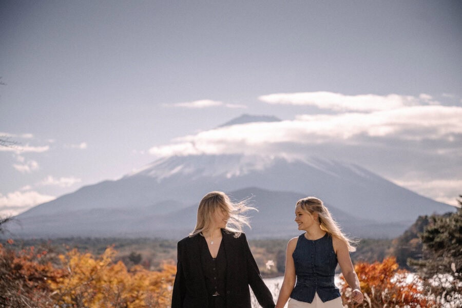 Hand in hand by Lake Shoji in late November, the couple walk past orange autumn leaves with snow-capped Mt Fuji behind them.