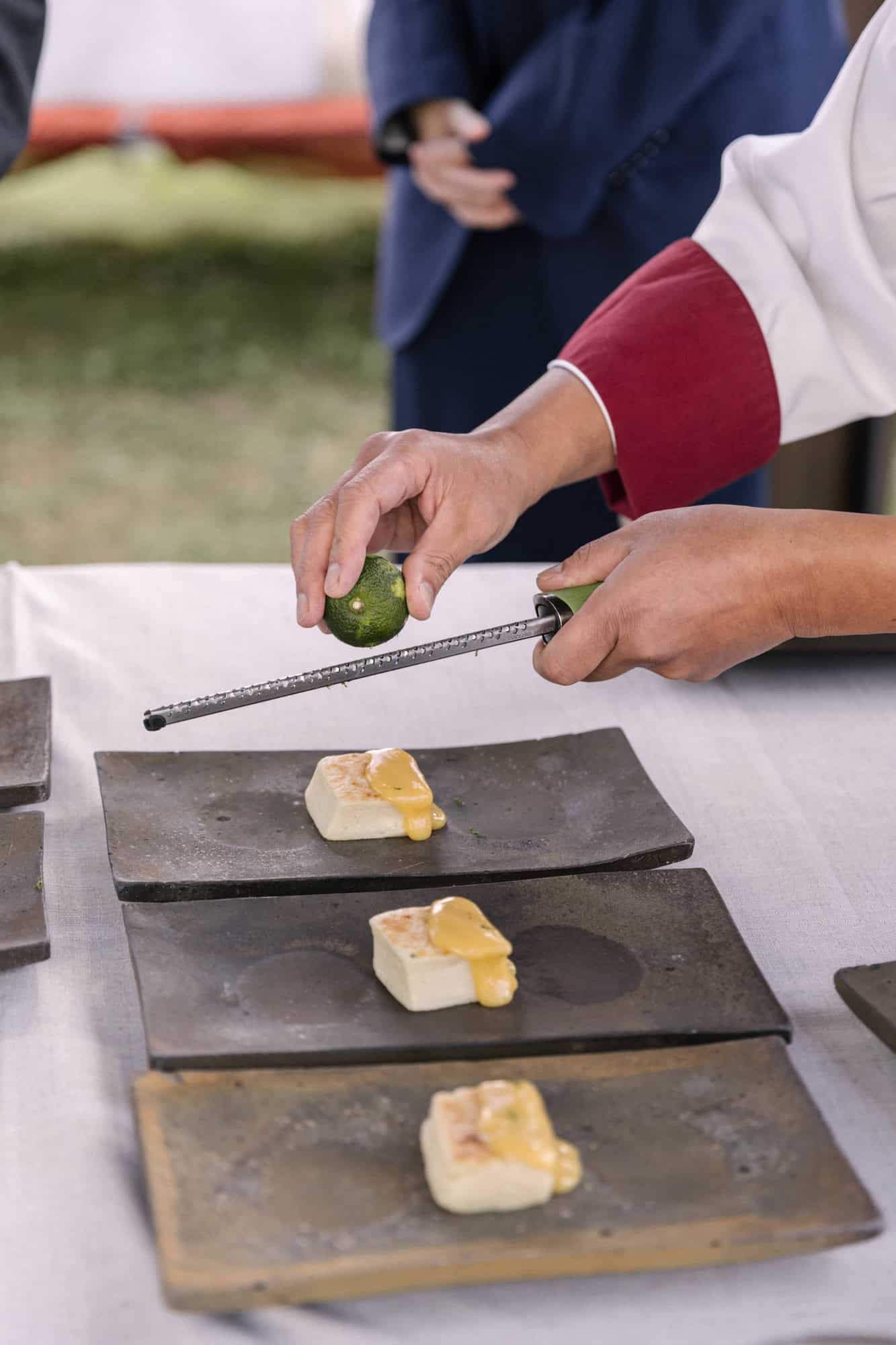 A chef zests lime over squares of tofu on slate plates as he prepares lunch for a vineyard wedding in Japan, near Sendai.
